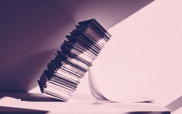 A tall stack of paper leaning and starting to topple.