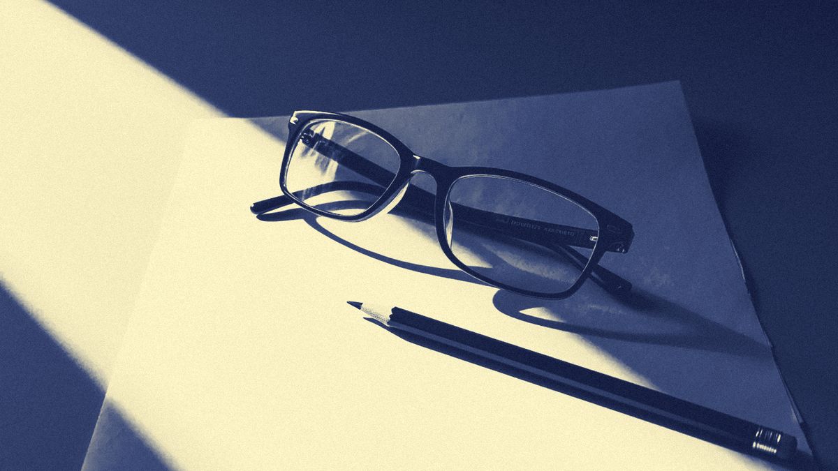 Reading glasses and a pencil resting on a sheet of paper.